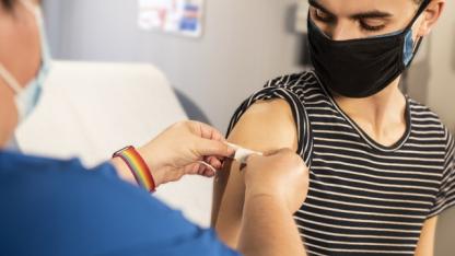 Eine Person bekommt nach einer Impfung ein Pflaster auf den rechten Oberarm geklebt