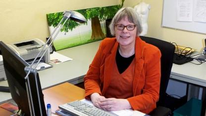 Person im roten Kost&uuml;m sitzt am Schreibtisch