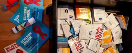 Kiste mit bunten Kondomen und davor liegen Postkarten